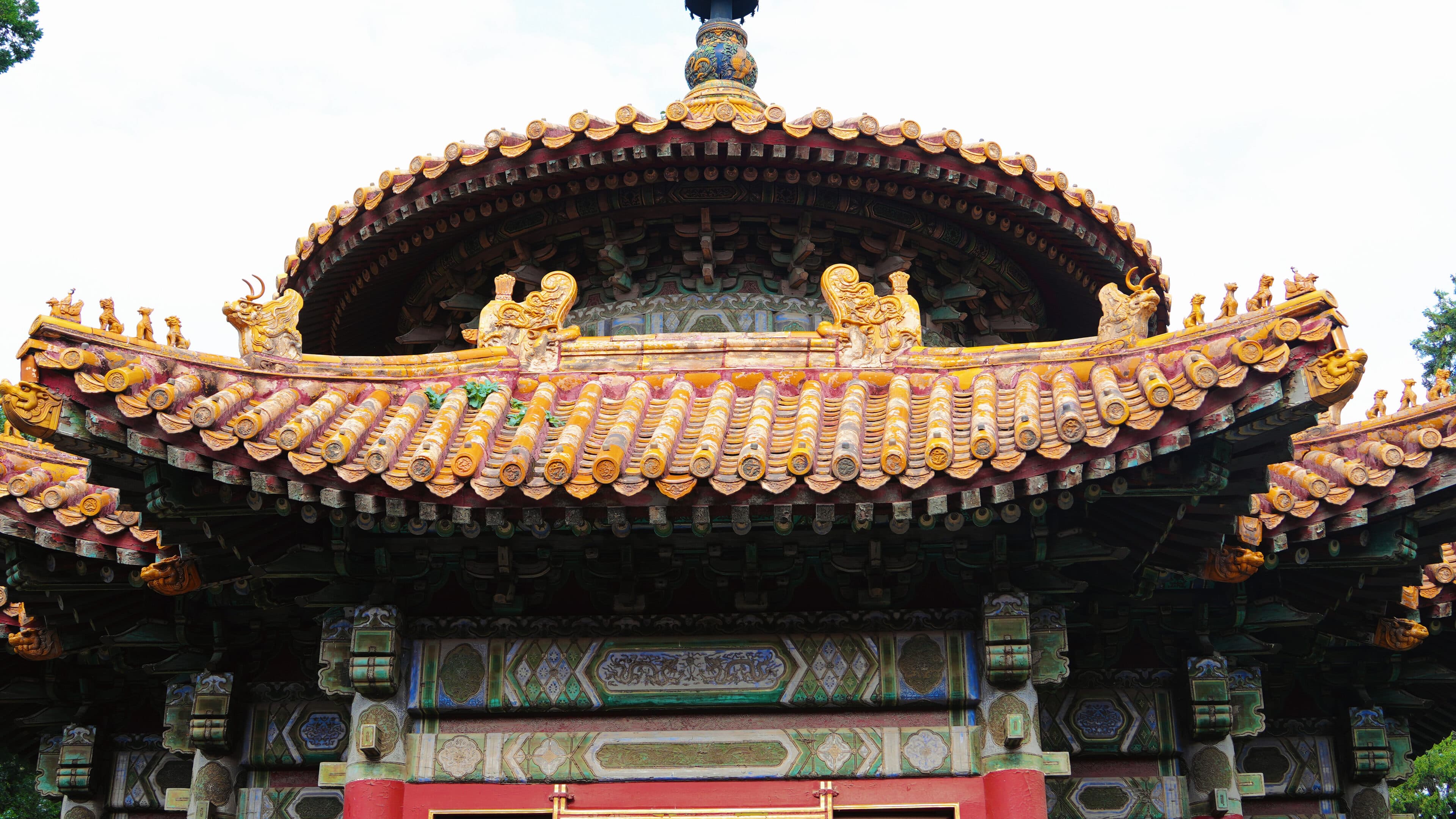 Tiered yellow glazed-tile roofs and painted brackets of a circular Beijing palace hall