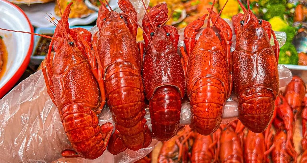 A table of red crayfish and chilli-heavy plates set up for sharing