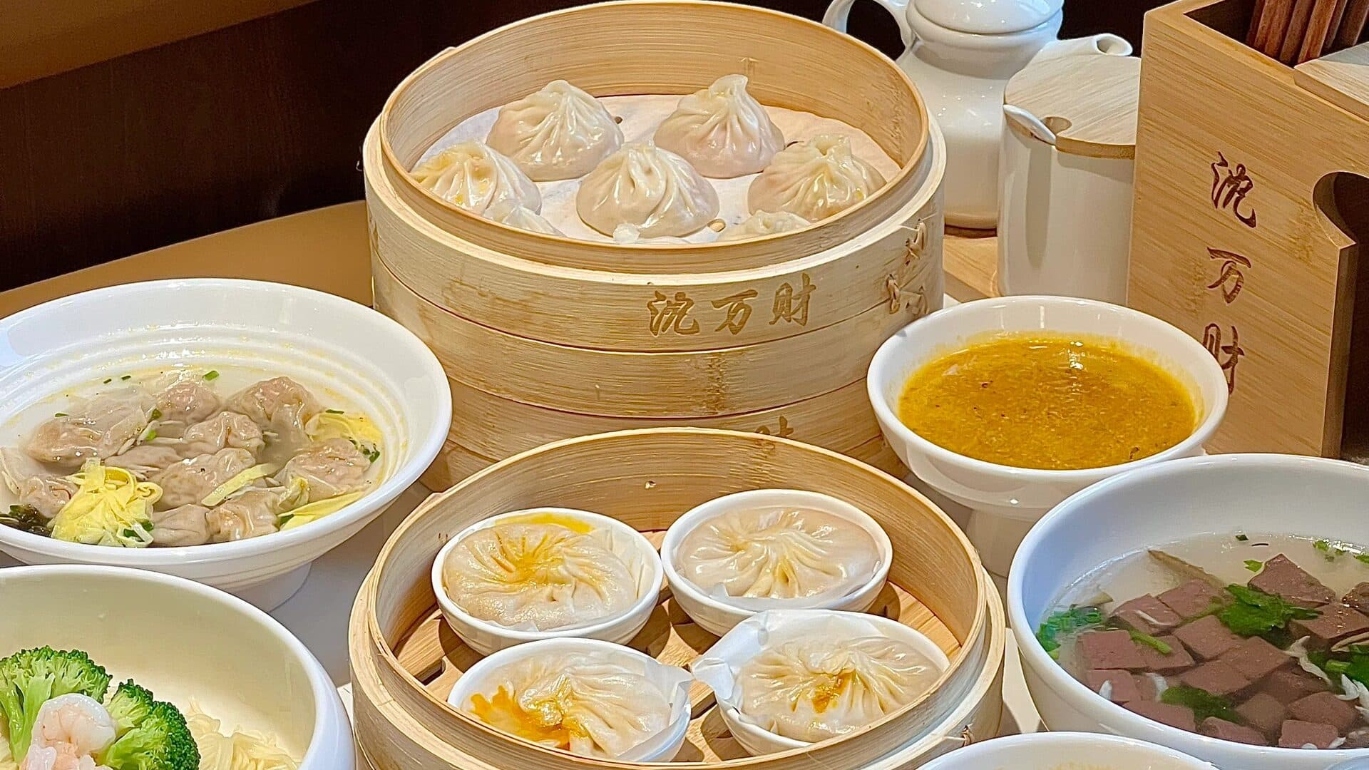 A tea-snack table of bamboo steamers, bowls of soup and small side dishes