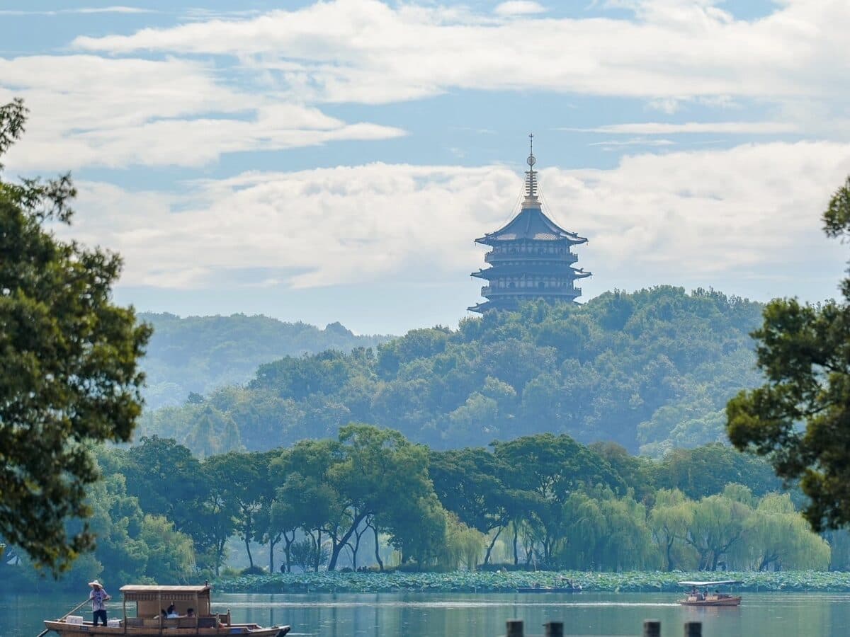 The Broken Bridge area of West Lake in Hangzhou: a stone arch bridge and the shore, with Baochu Pagoda above the tree line beyond