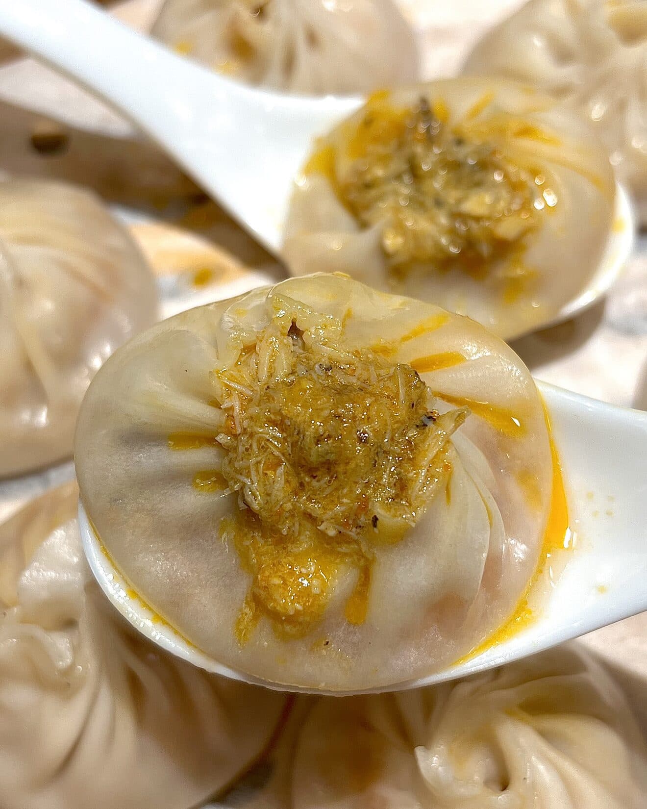 A close-up of a soup dumpling topped with crab roe in a steamer