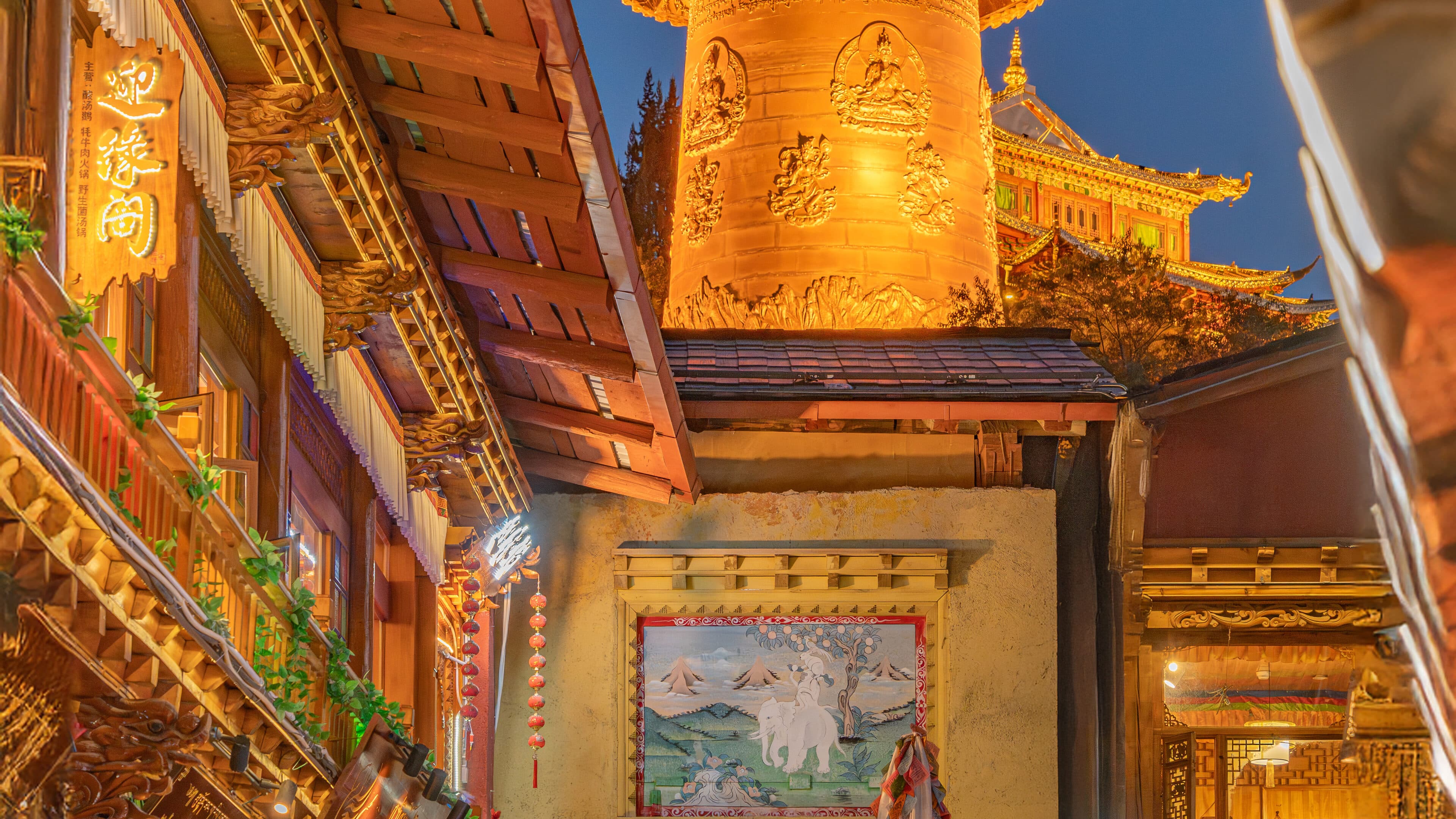 A lantern-lit timber pavilion at night, with gilded relief columns and red lanterns