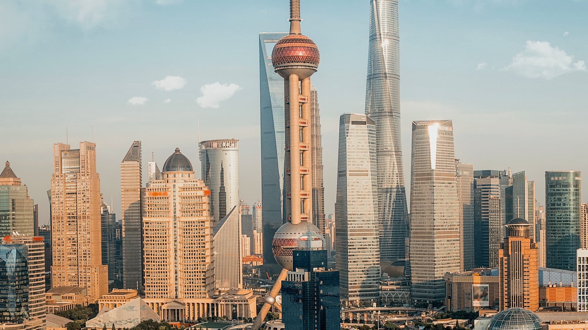 Shanghai's Lujiazui skyline by day: the Oriental Pearl Tower and a row of skyscrapers under cloud