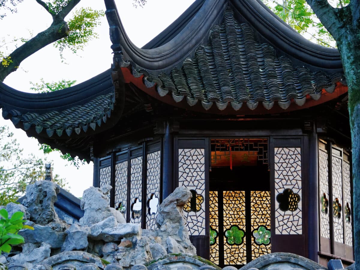 A corner of a Suzhou garden: a waterside pavilion, rockery and old trees along a whitewashed bank