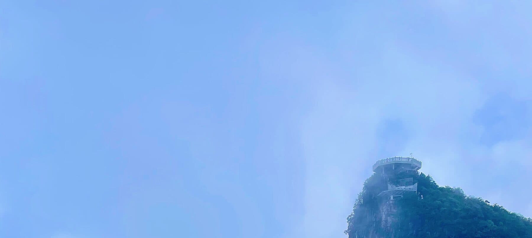 Steep cliff peak with a circular viewing platform in the mist