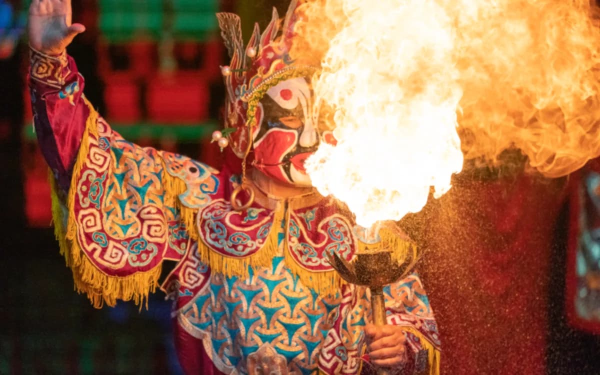 A Sichuan opera performer in a painted costume breathing fire