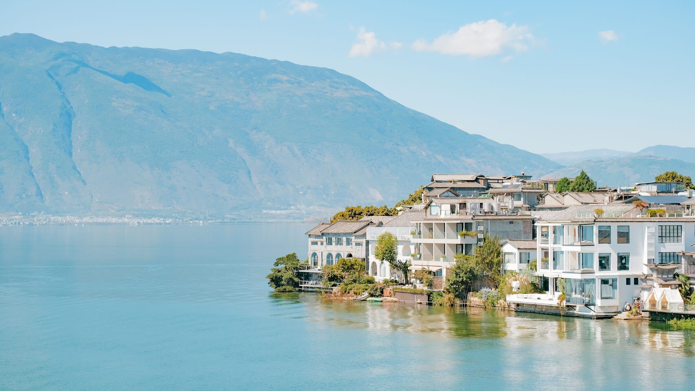 White-walled village houses on the shore of Erhai Lake, with the Cangshan range behind