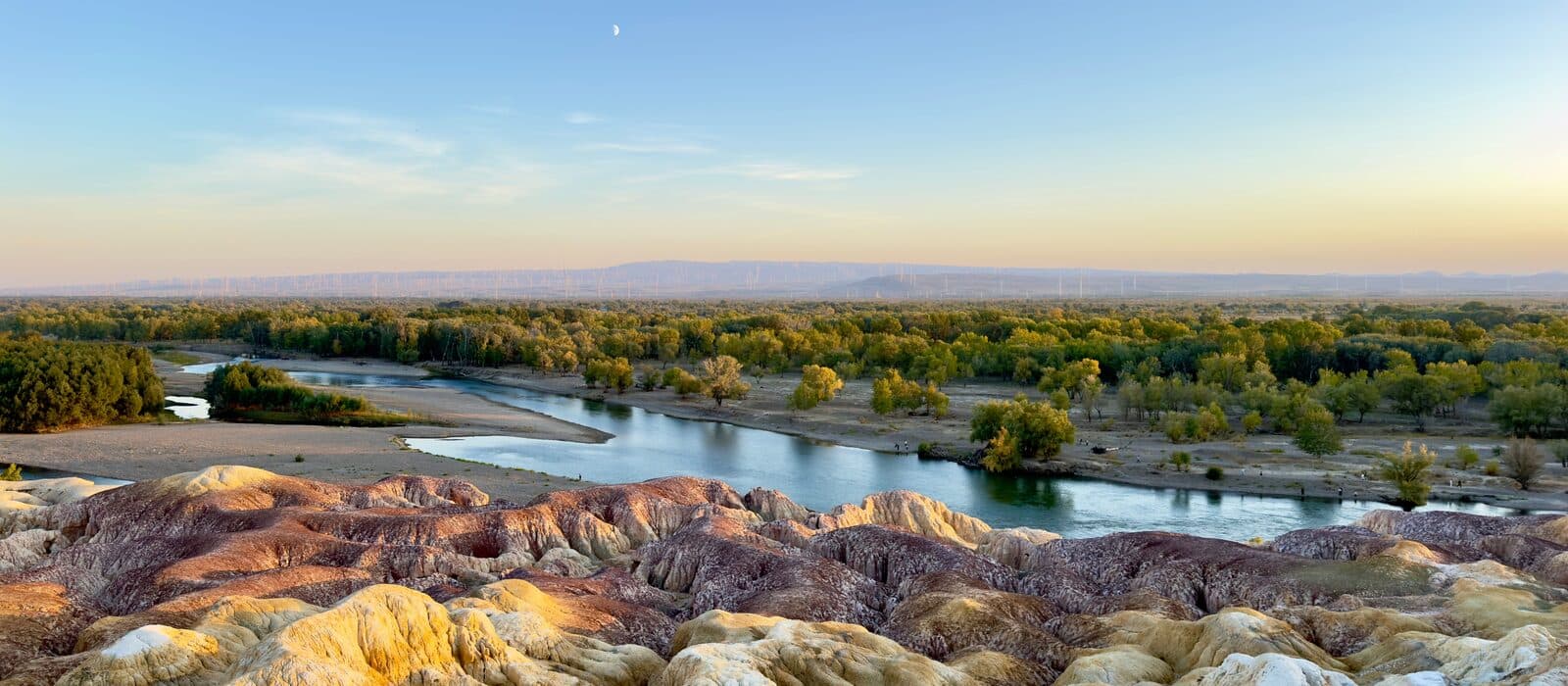 Banded eroded bluffs above a meandering river with autumn foliage