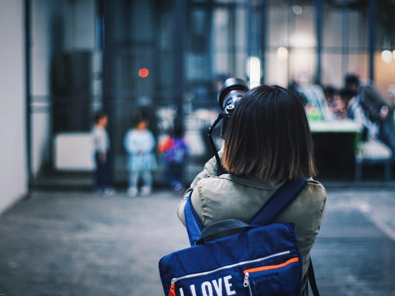 A gallery hall in the 798 Art District: a visitor photographing exhibits, seen from behind