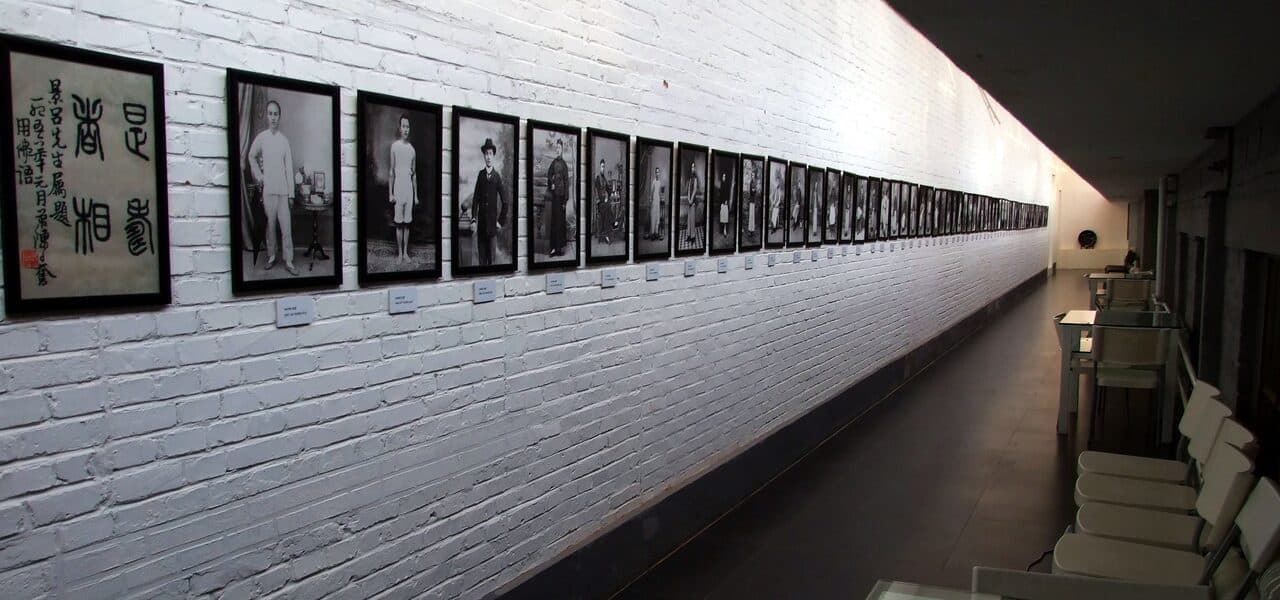 A photography exhibition in the 798 Art District: a row of black-and-white portrait photographs along a white brick wall, receding down the corridor