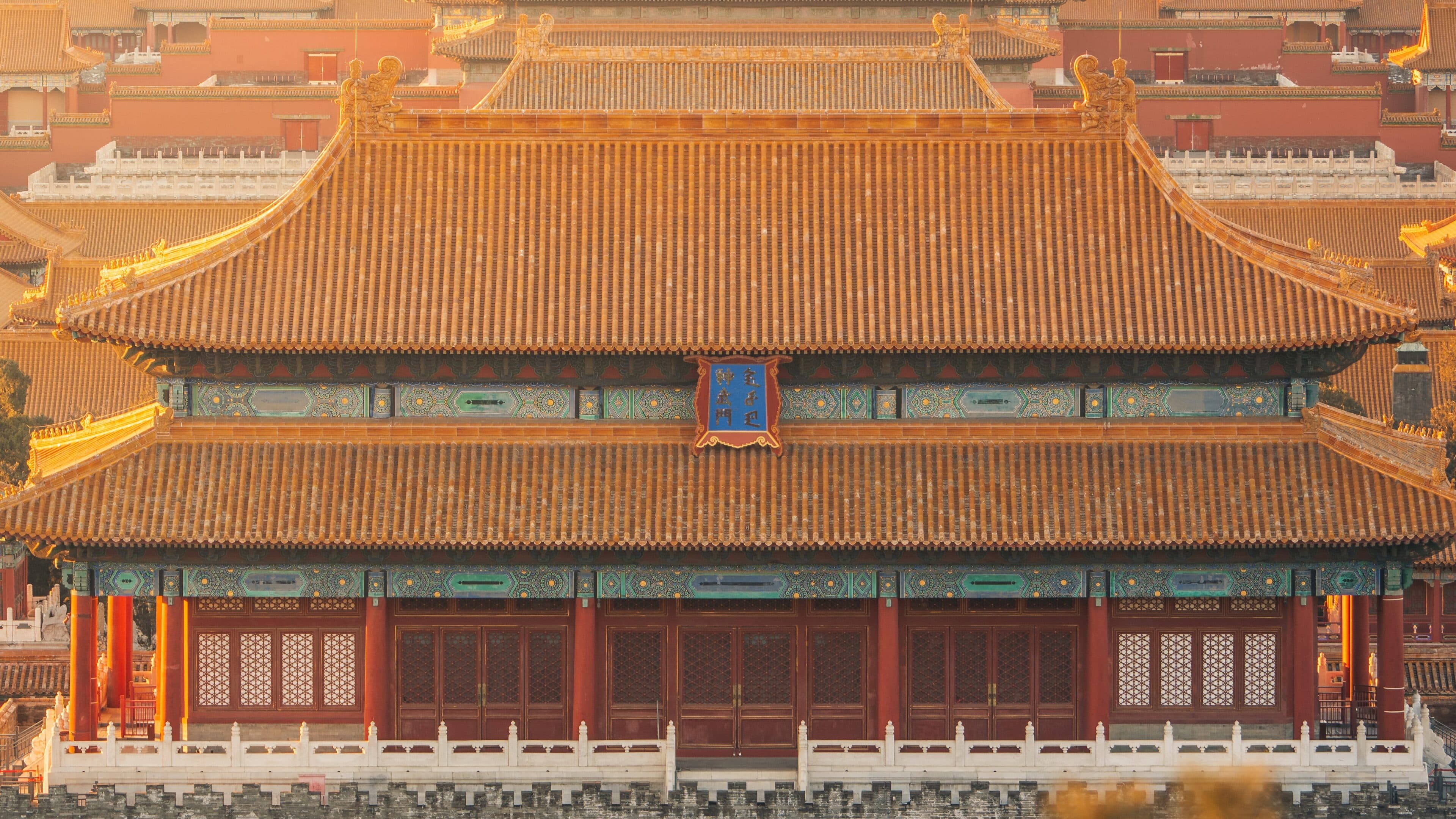 Tiered yellow glazed-tile roofs, painted brackets, and red columns and lattice doors