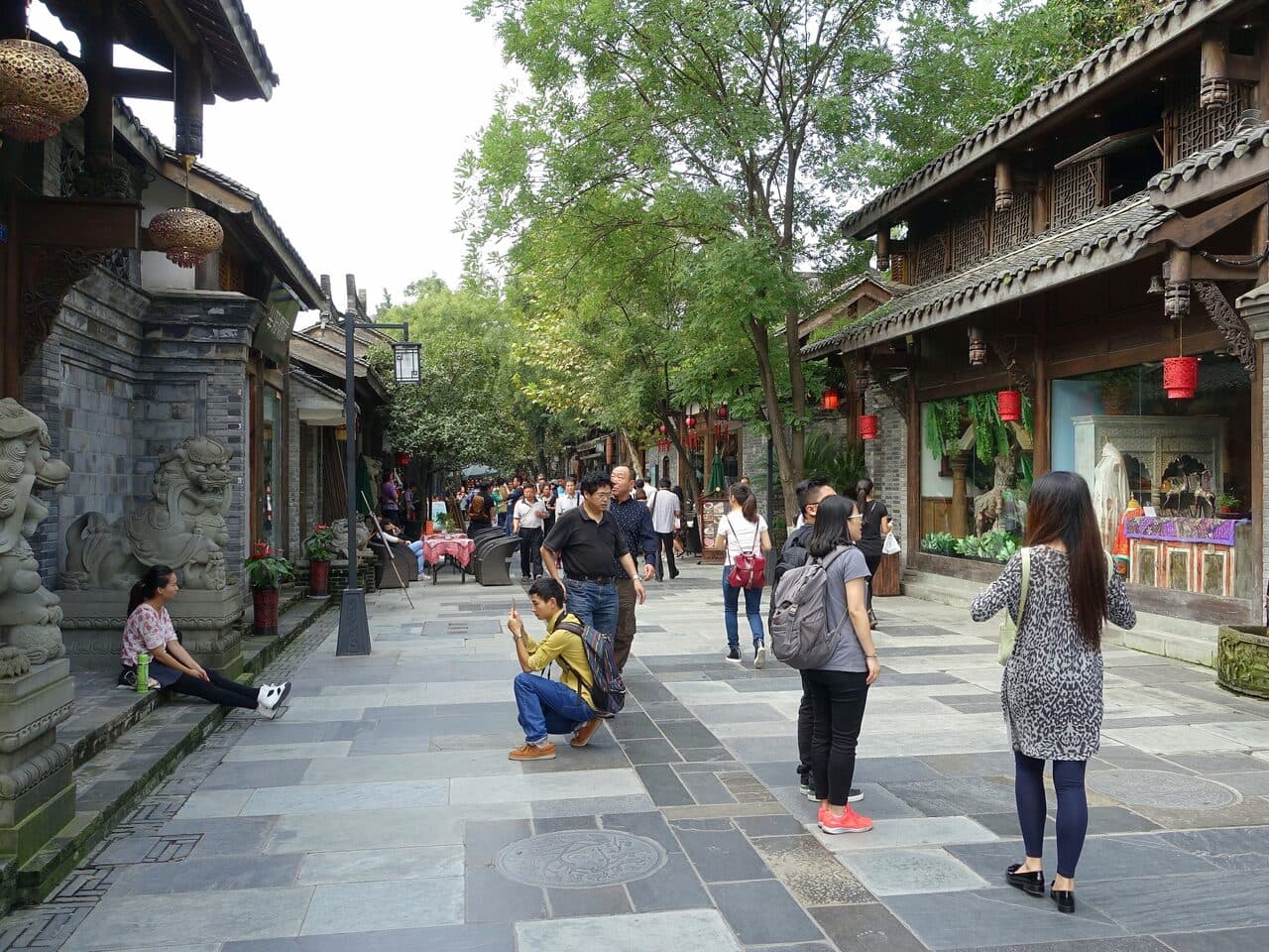 Kuanzhai Alley in Chengdu: a flagstone lane lined with grey-tiled eaves, walkers among trees and red lanterns