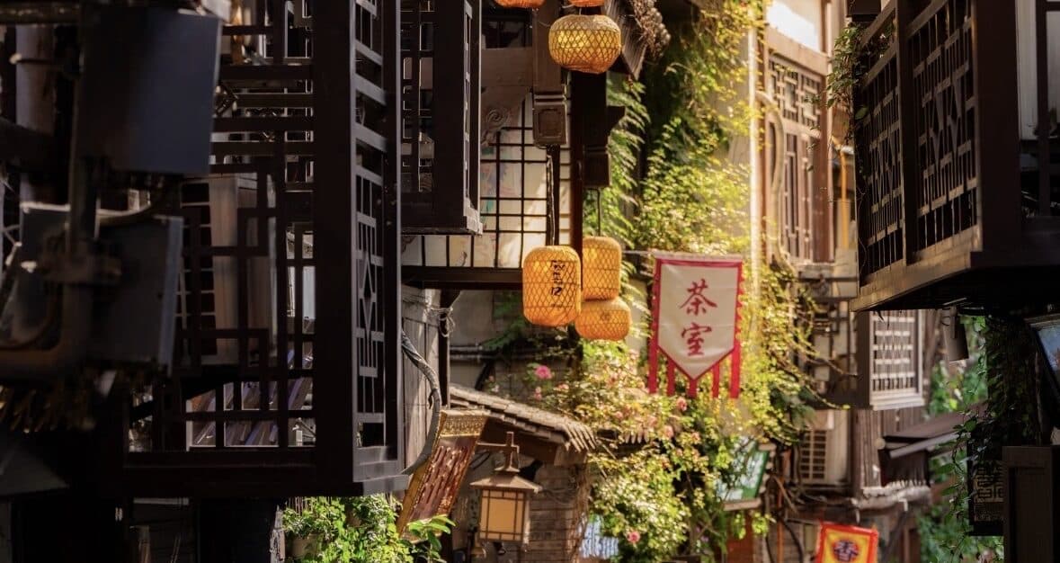 A timber shopfront lane in the old town with red lanterns and a teahouse banner under the eaves