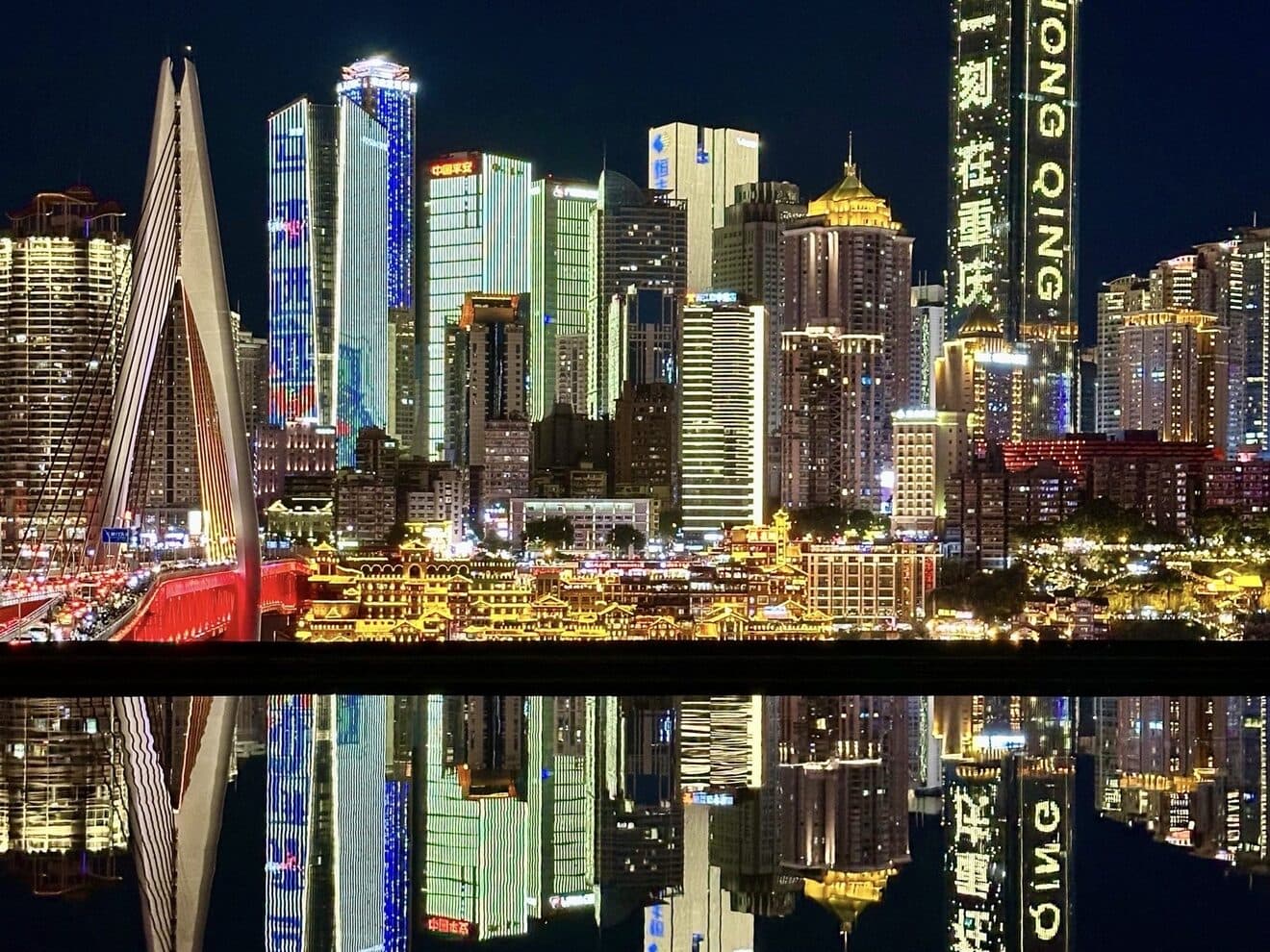 Downtown Chongqing's lit towers mirrored in the river at night