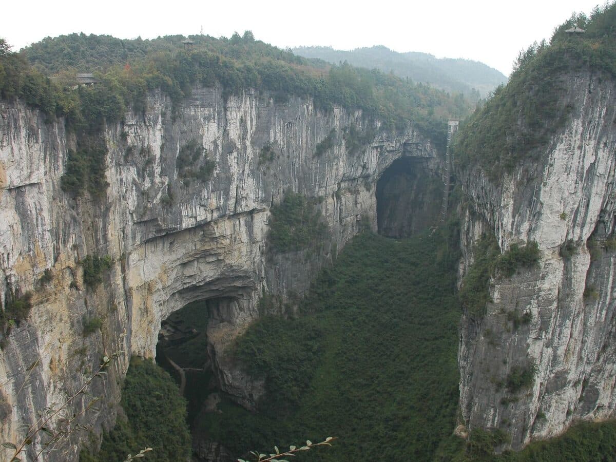 Wulong Three Natural Bridges: a natural bridge above a deep karst gorge framed by forested cliffs