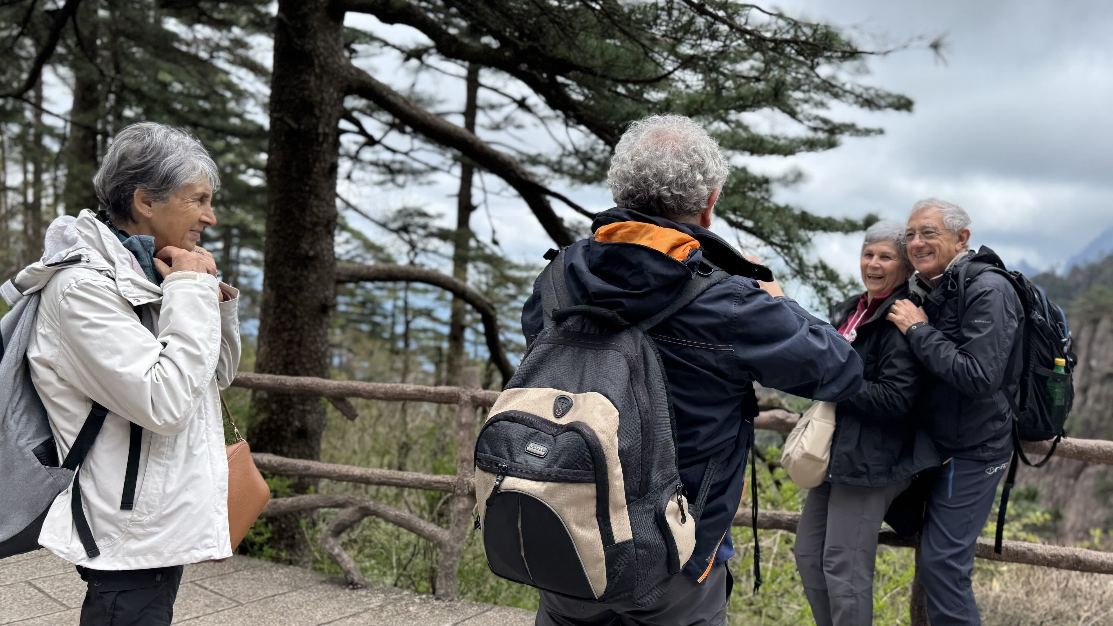 Visitors by a mountain railing, one of them photographing the others from behind