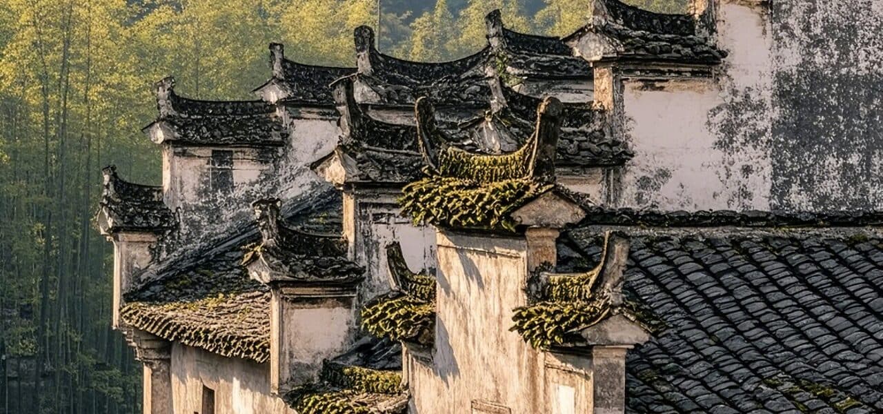 Huizhou houses with stepped horse-head gables along whitewashed walls, with a bamboo hillside behind
