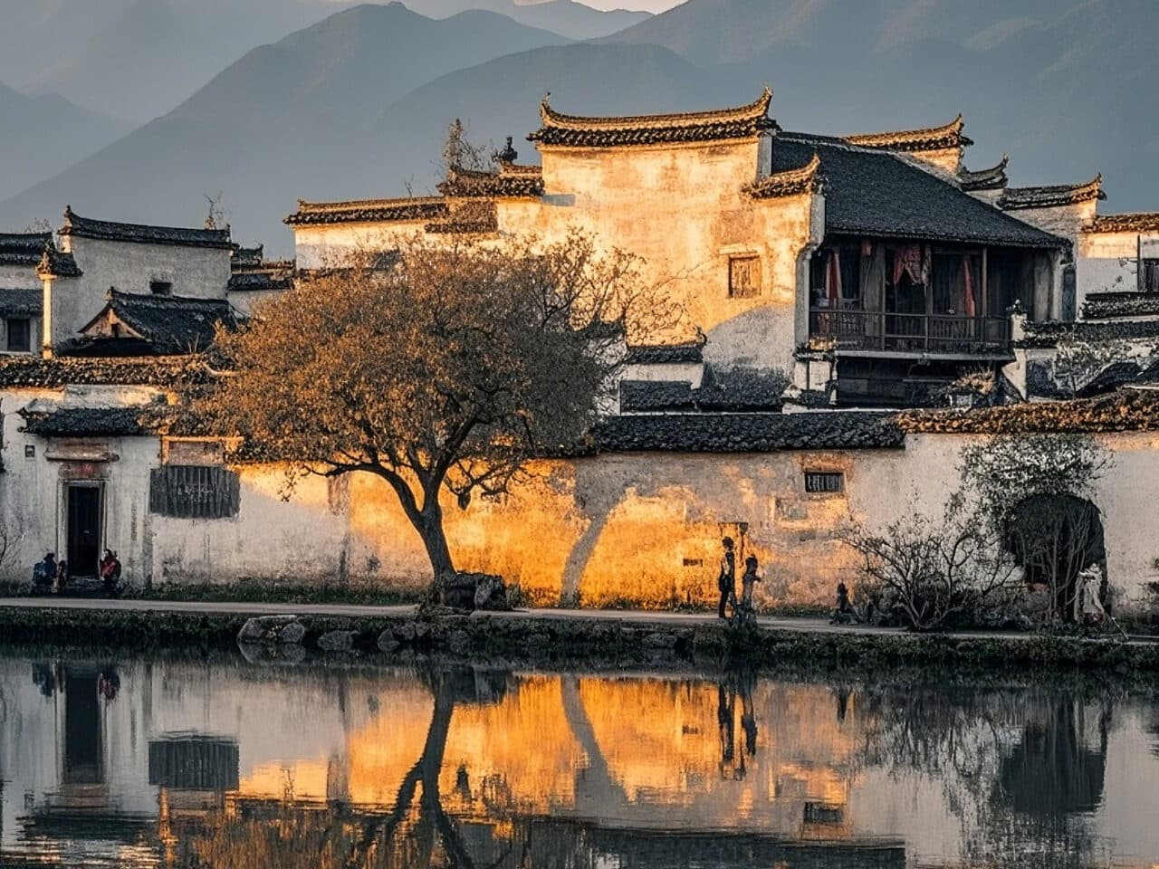 A Hui-style village: white-walled, dark-tiled houses along a pond, their outlines mirrored in the water