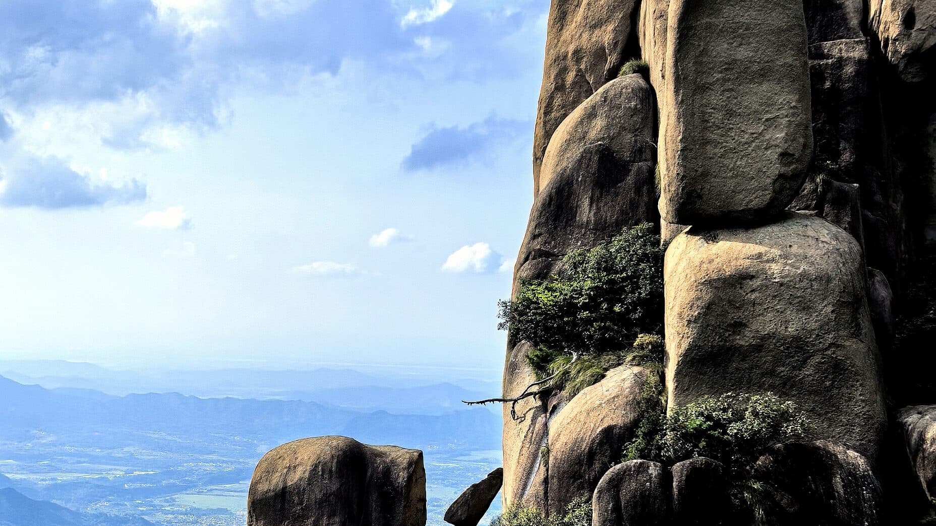 Huangshan's granite faces and cloud sea: pines rooted in the cliff, distant ridges showing between banks of cloud