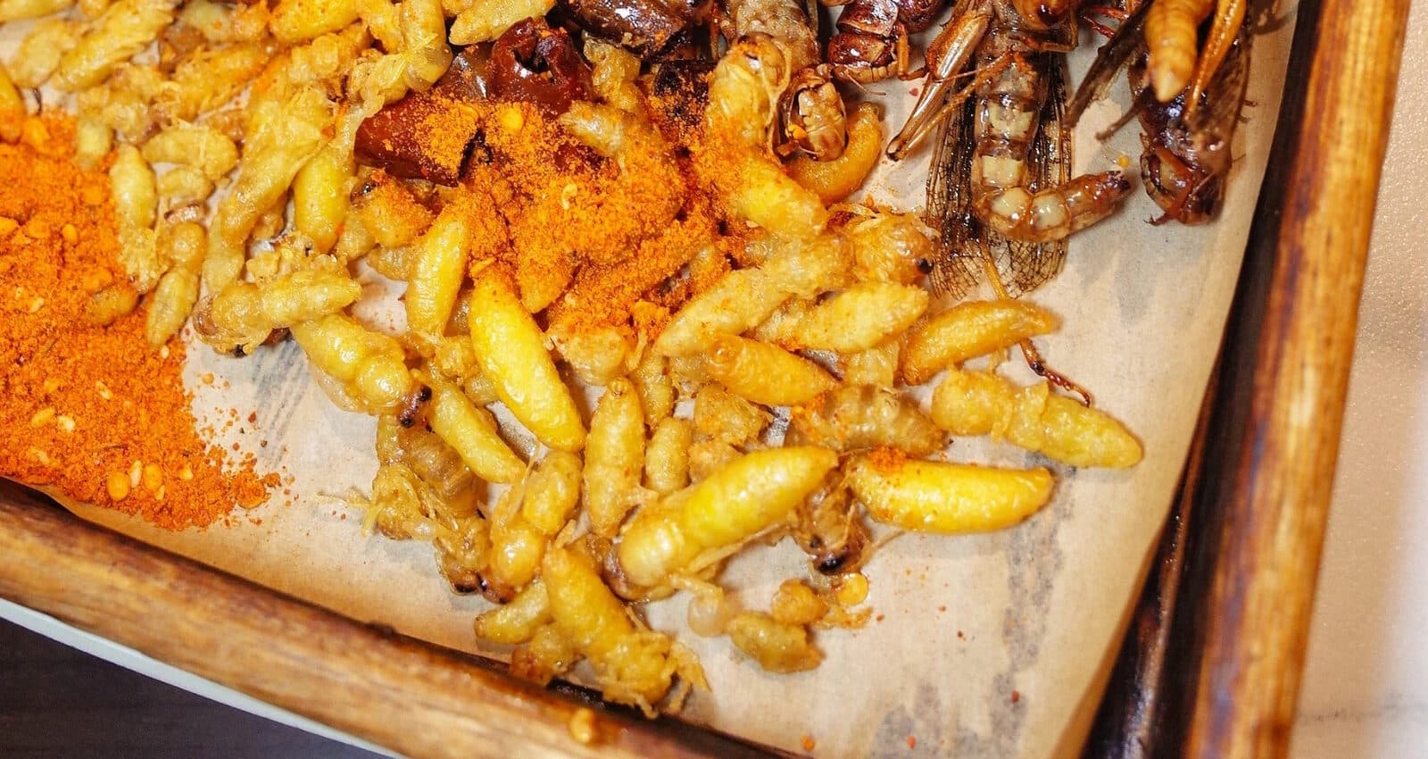 Golden fried strips on a wooden tray with a dry chilli dip beside them