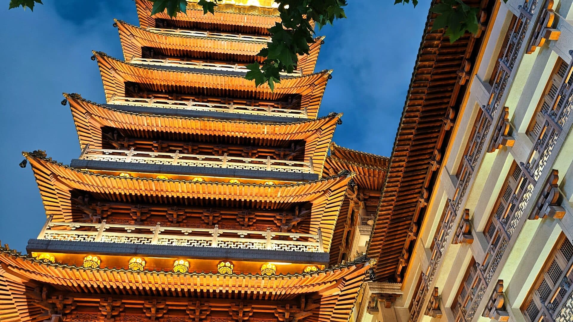 The seven-storey golden pagoda of Jing'an Temple, its eaves rising between the blue sky and modern glass towers behind