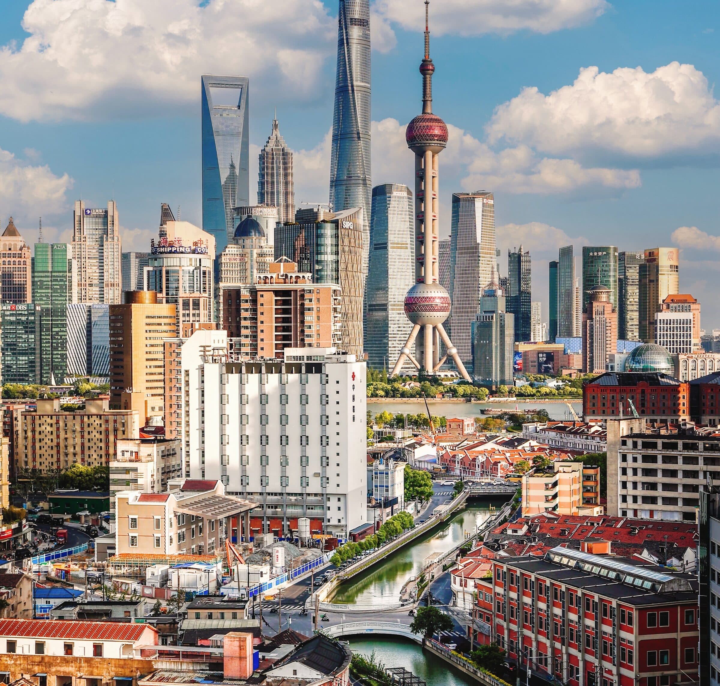 Shanghai's Lujiazui skyline in daylight: the Shanghai Tower, Jin Mao Tower and Shanghai World Financial Center rising in a row under cloud