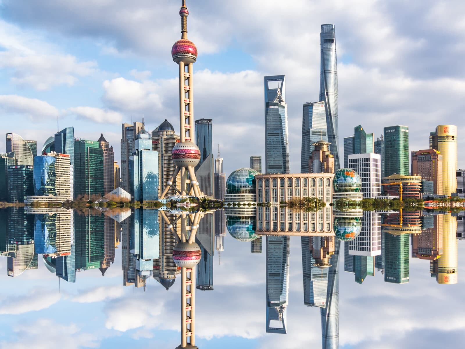 Shanghai's Lujiazui skyline in daylight mirrored in the river, the towers lining the waterfront