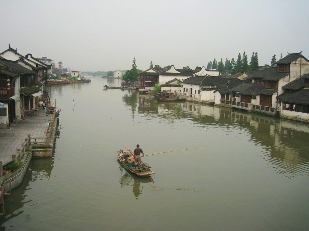 A canal in Zhujiajiao old town: a boatman poling along between white-walled, dark-tiled houses on the water