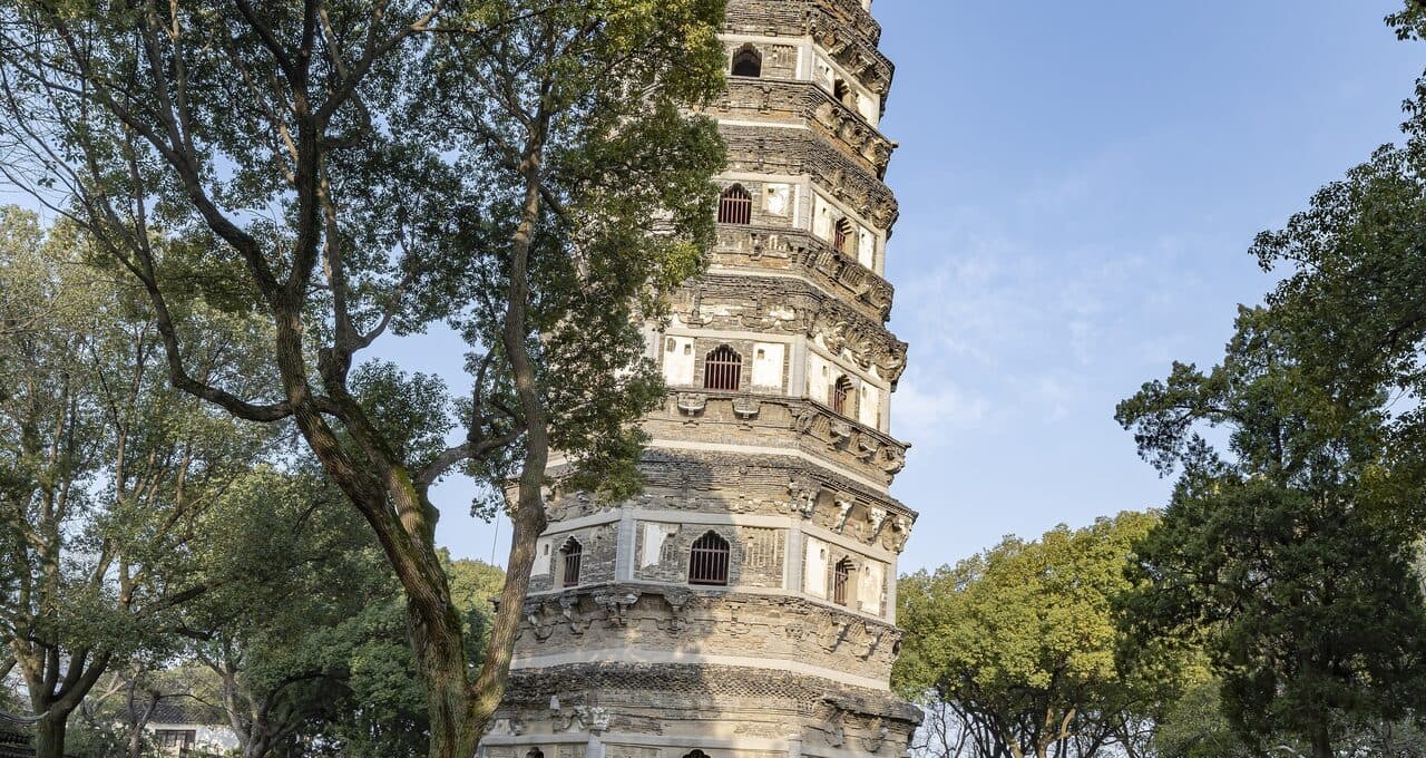 The Tiger Hill Pagoda: a leaning multi-storey brick tower standing among trees, its tiers visible storey by storey