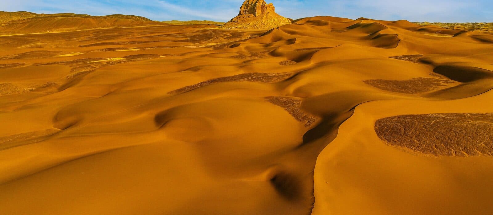 An open field of golden dunes under a clear blue sky
