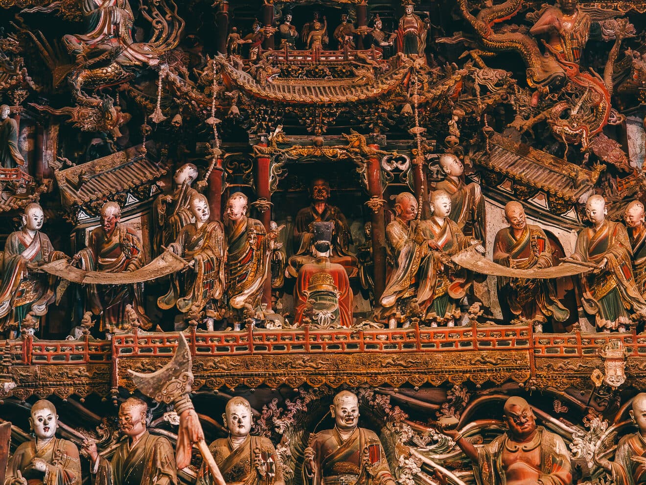 Rows of carved stone relief panels with figures and pavilion motifs