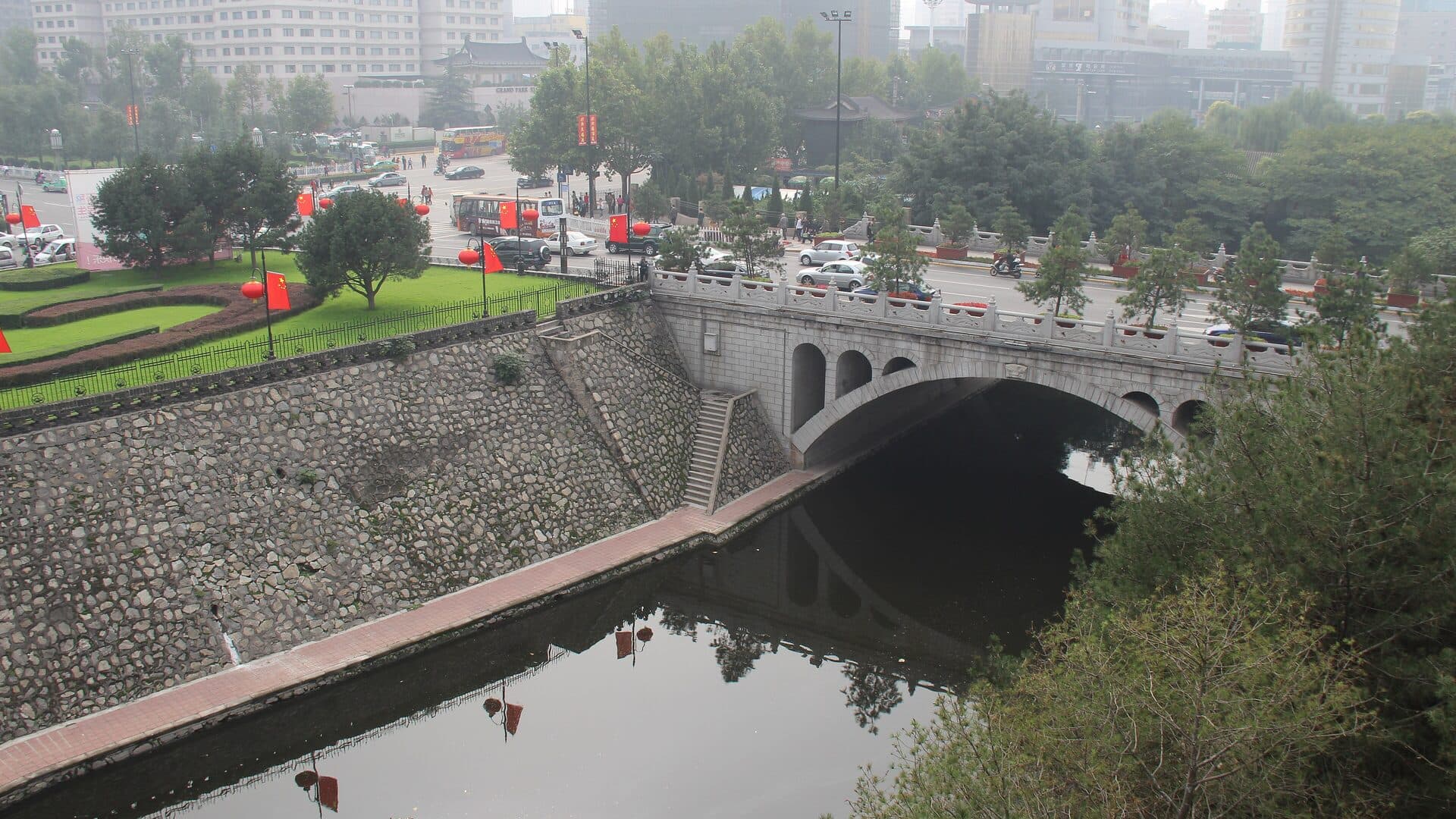 The moat outside Xi'an's South Gate: a stone arch bridge over the water, with the brick city wall and its green belt beyond