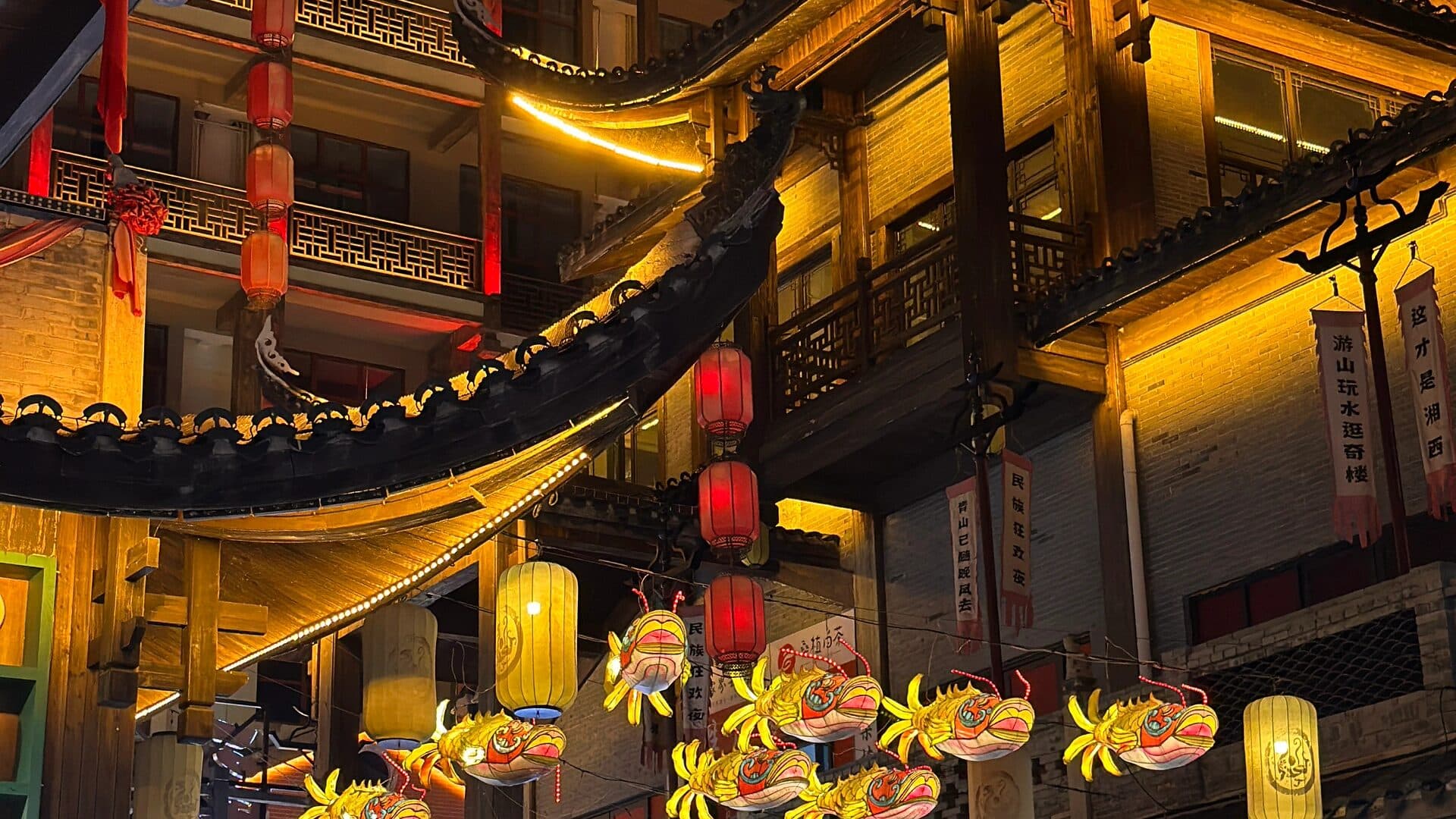 Lantern-lit wooden shopfronts and hanging lanterns on a Zhangjiajie old-style night street