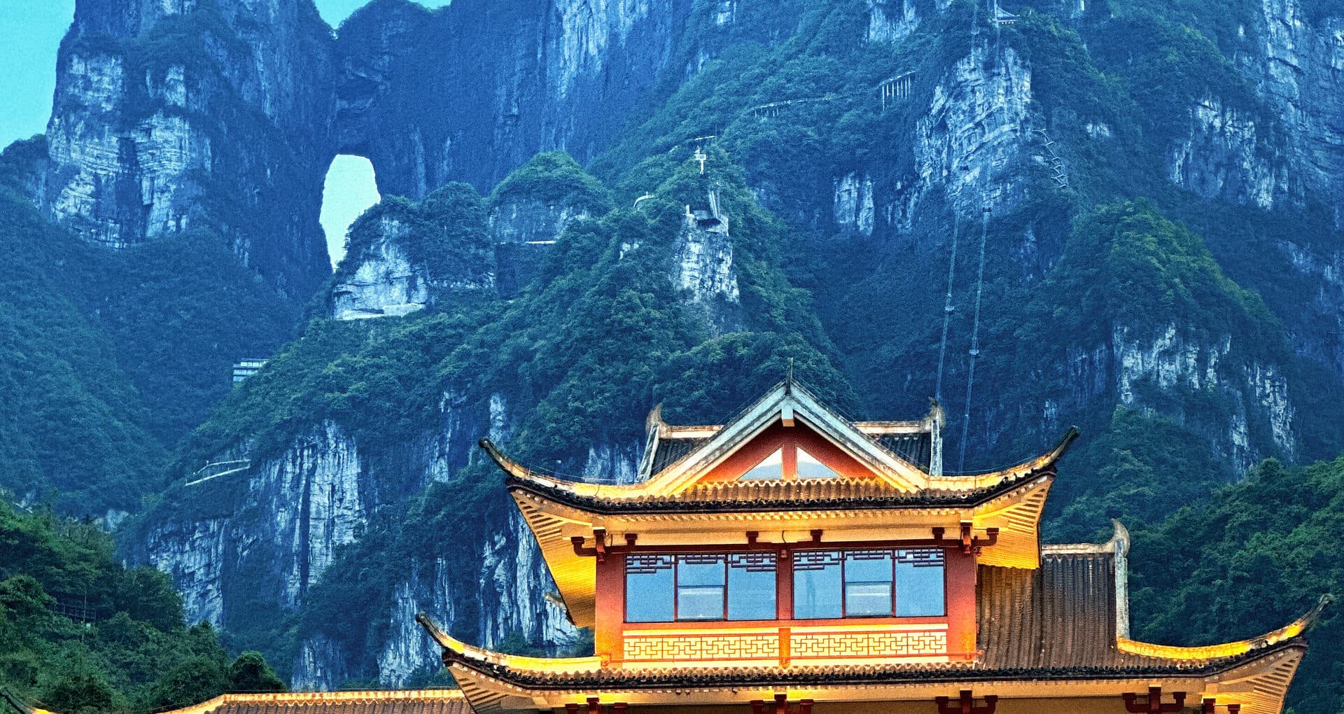 Timber-framed pavilion with tiered roofs below the cliff