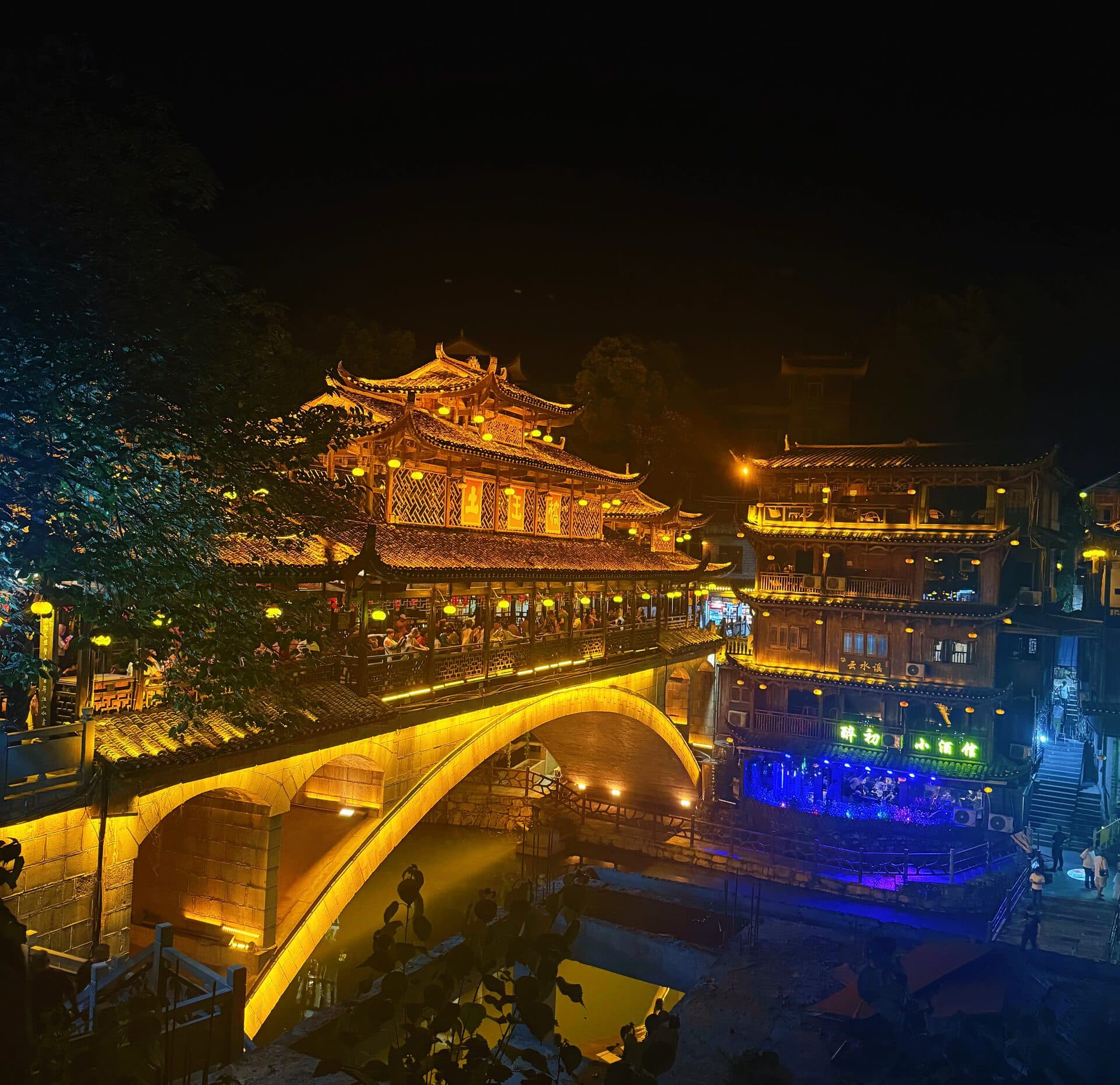Night view of the covered bridge and lit houses along the stream