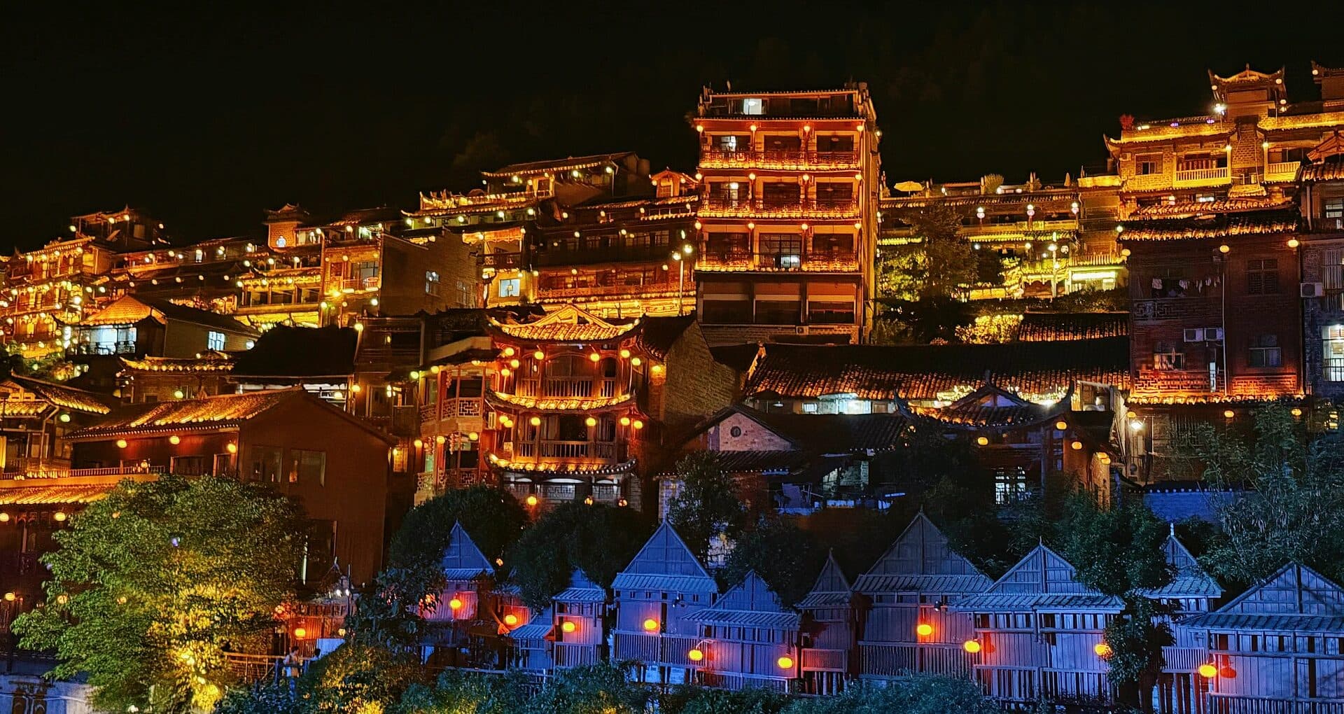 Lit hillside houses of the old town seen from a night path