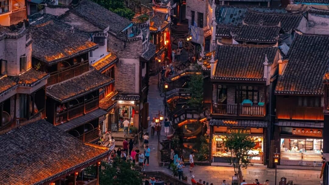 Fenghuang Ancient Town lanes with wooden shopfronts lit at dusk