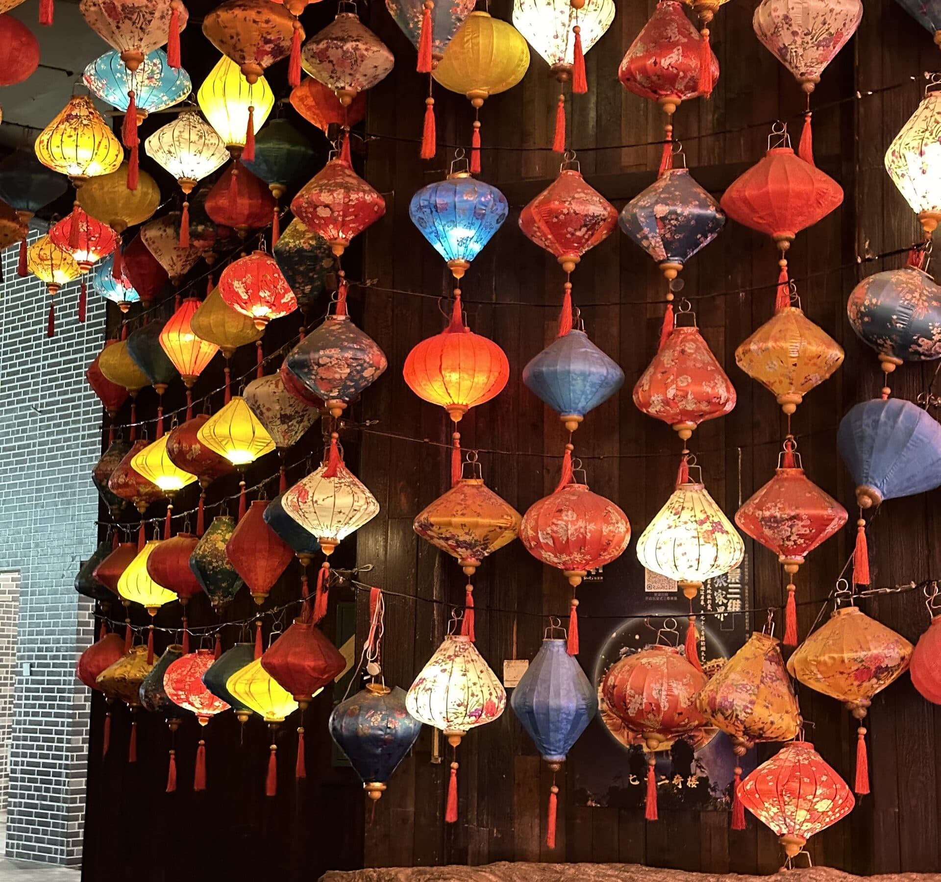 Strings of painted lanterns glowing against a dark timber wall