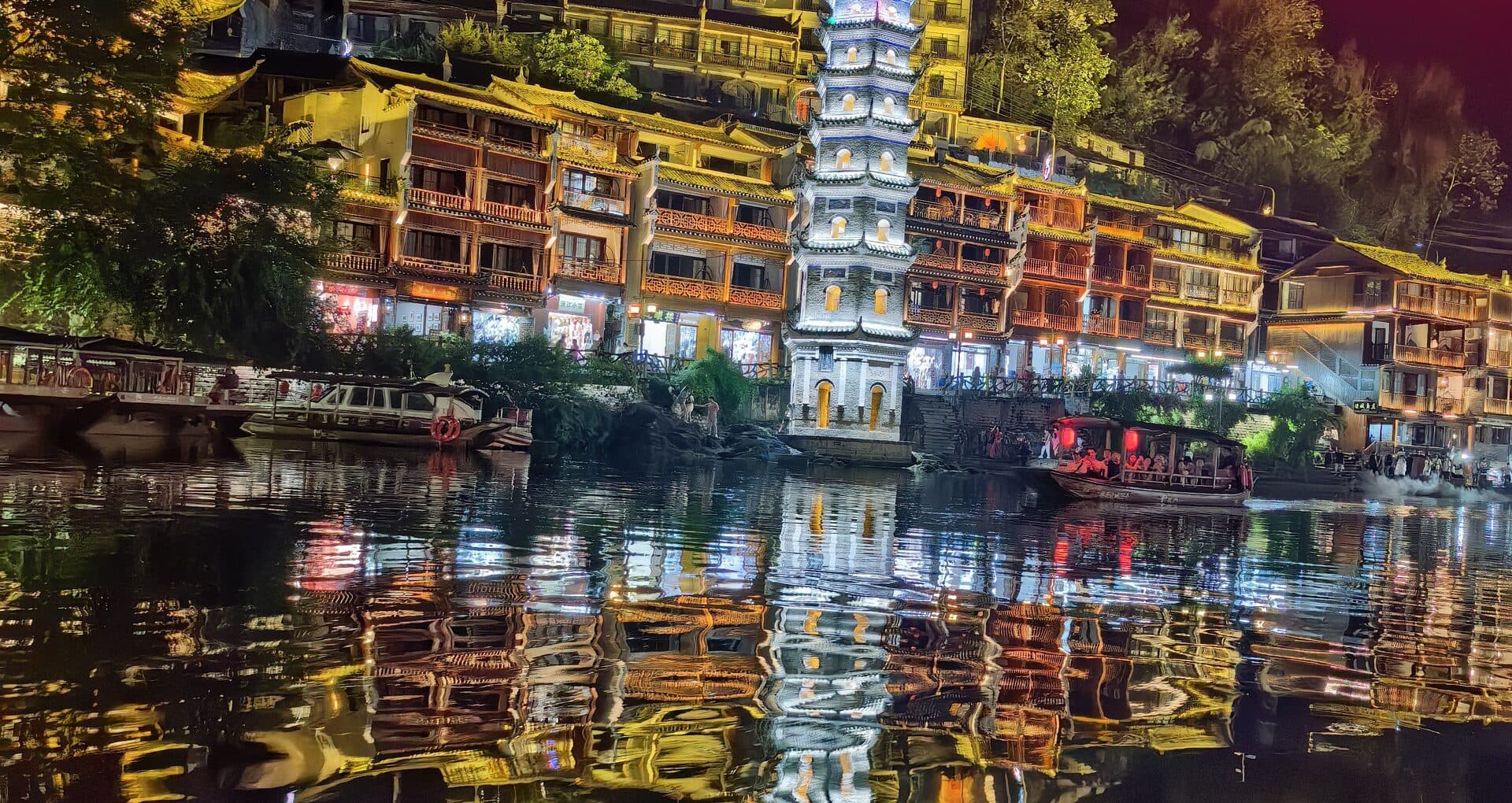White pagoda and lit stilt houses above the river at night