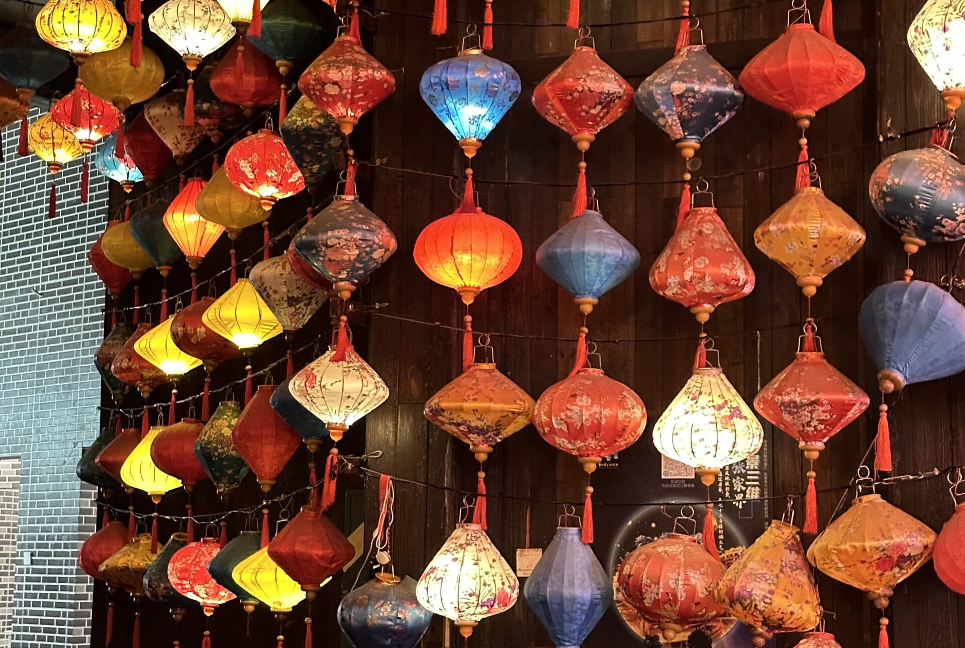 Coloured lanterns strung along a dark wooden wall at night