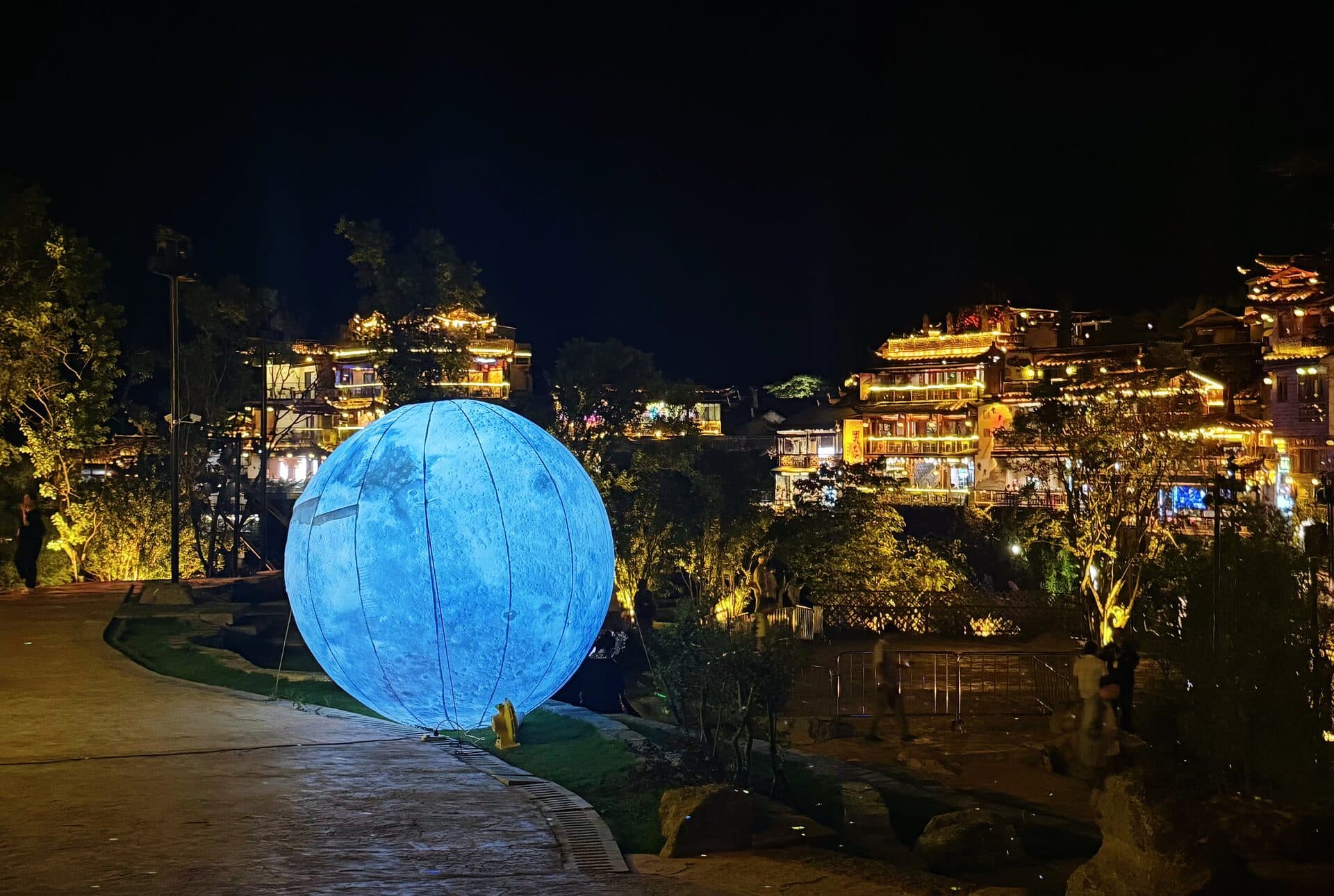 Night walkway lined with glowing moon-shaped lanterns
