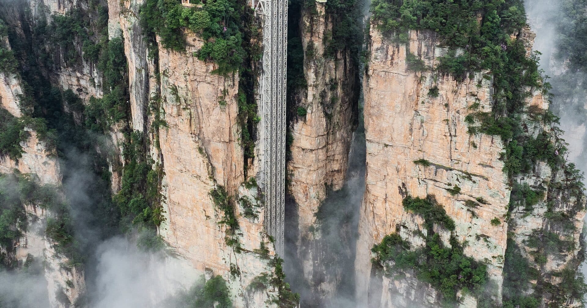 The Bailong Elevator shaft climbing the sandstone cliff face above a misted valley