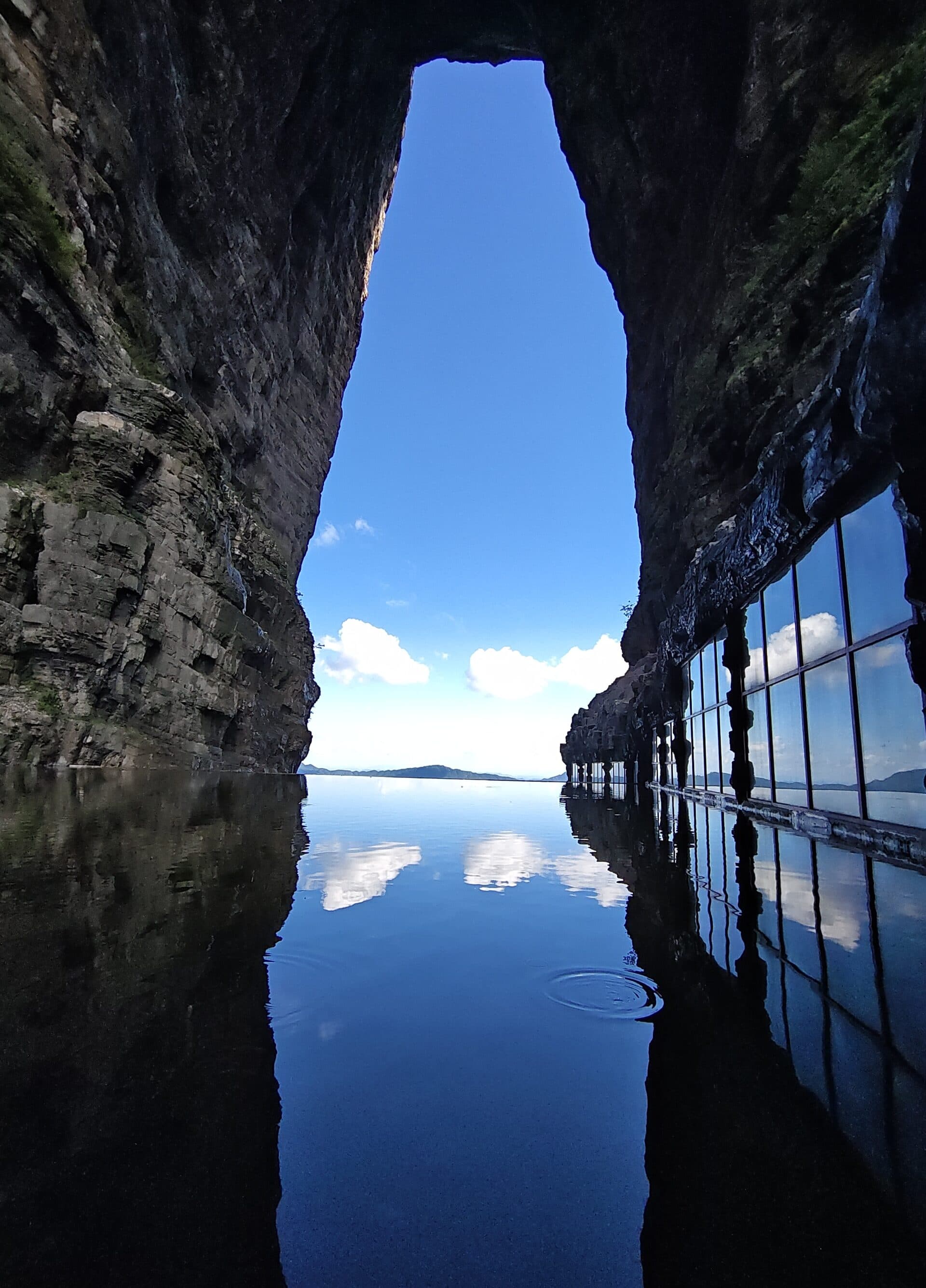 Narrow canyon water reflecting the sky between dark rock walls