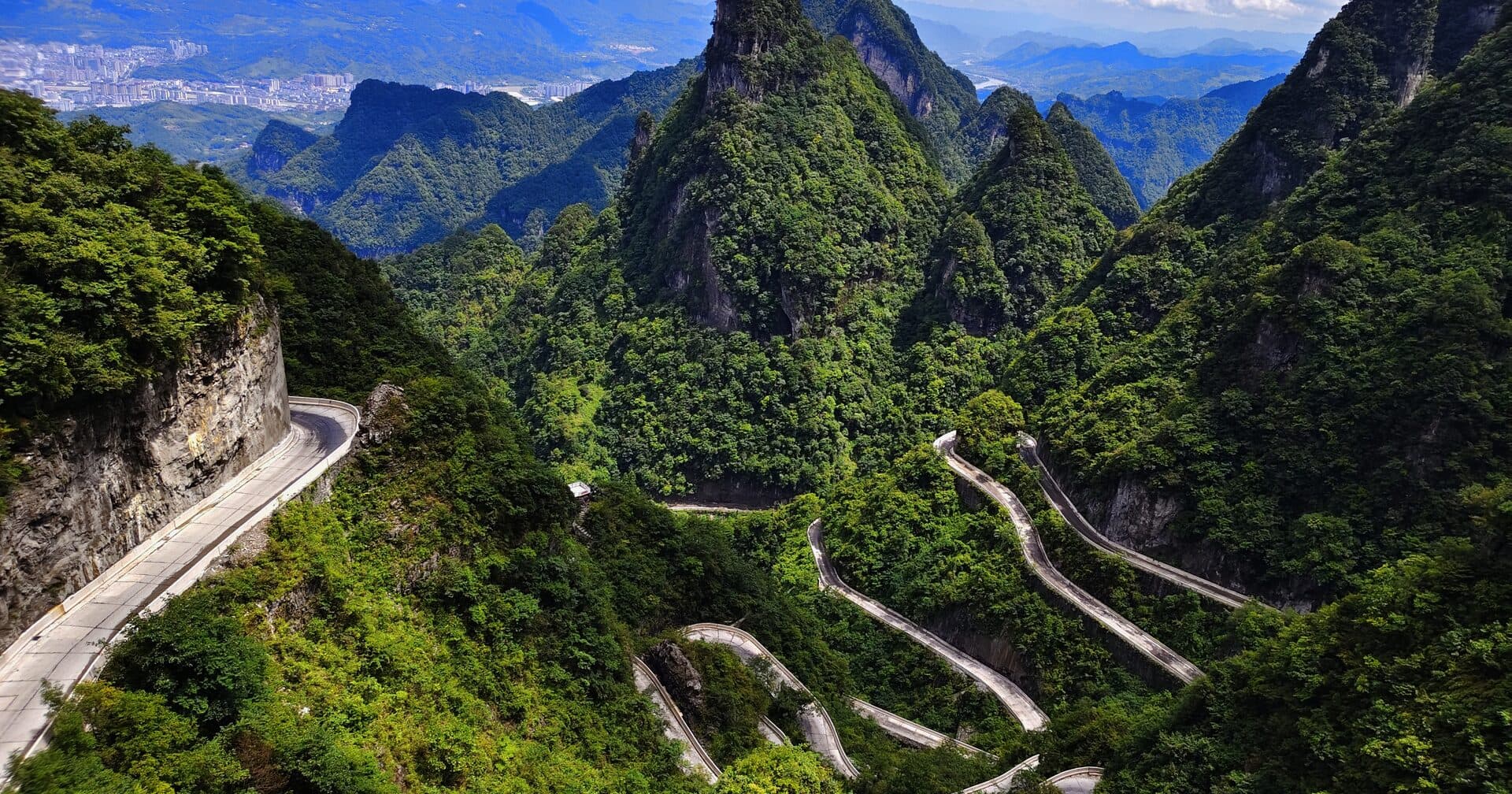 The Tianmen switchback road descending between green karst peaks toward the city
