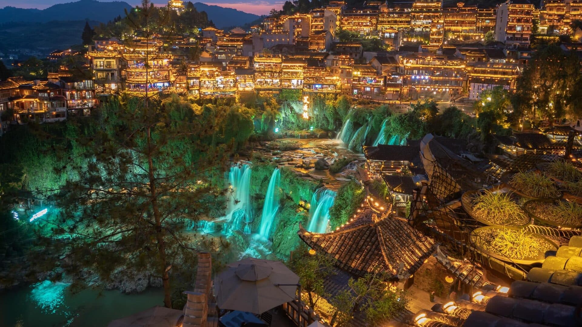 Furong Town stilt houses and the tiered waterfall lit at night