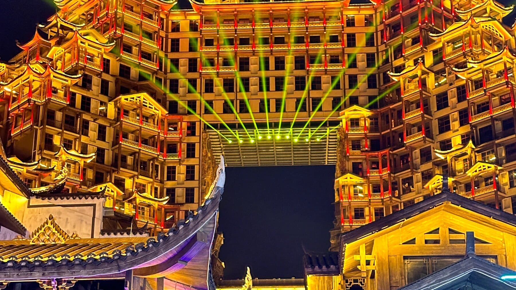Gold-lit tiered building complex with light beams on a Zhangjiajie night