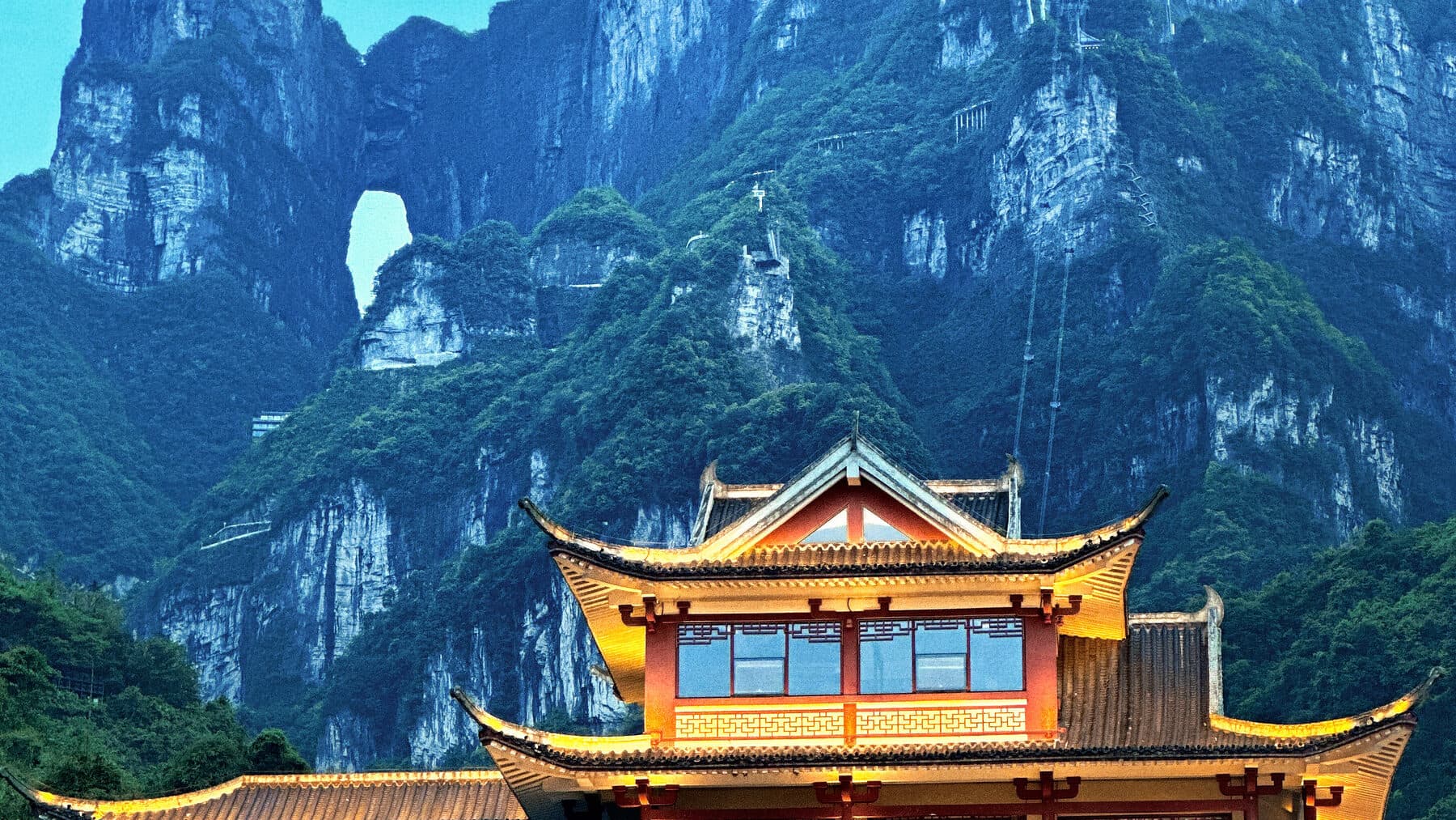 Golden-roofed pavilion beneath green cliffs and the Tianmen cave arch