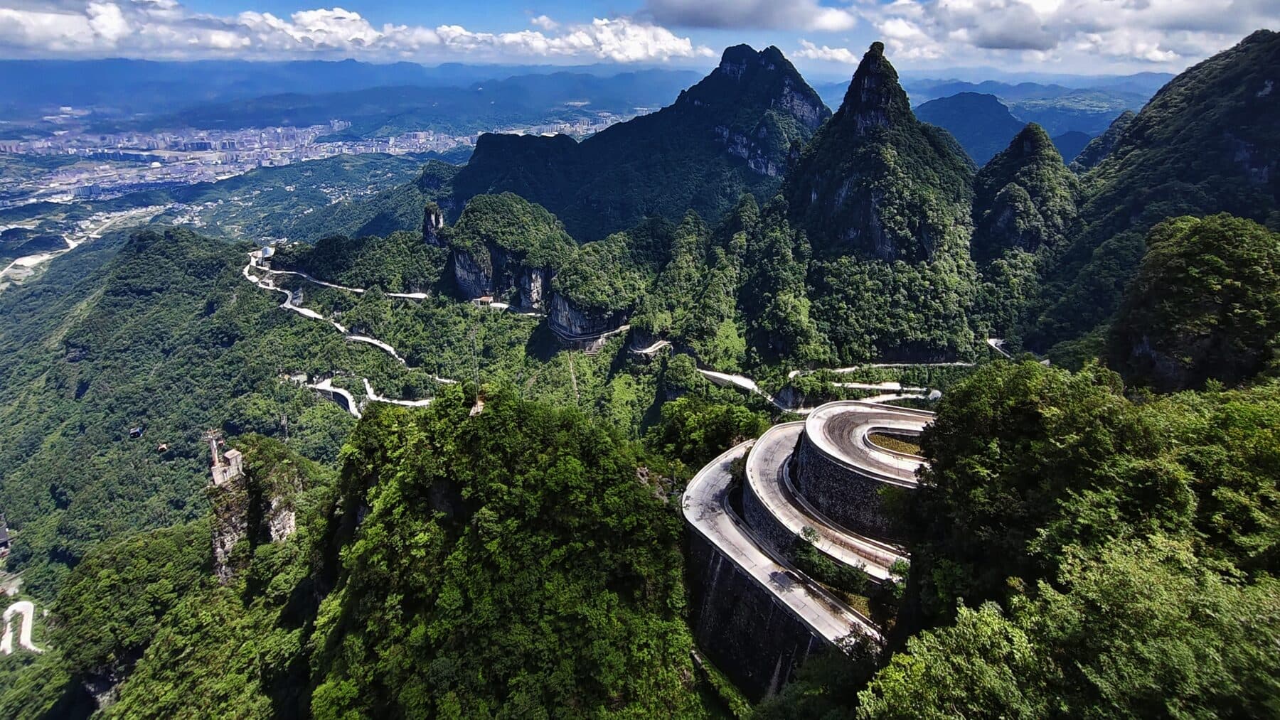Switchback mountain road above Zhangjiajie with the city on the plain below