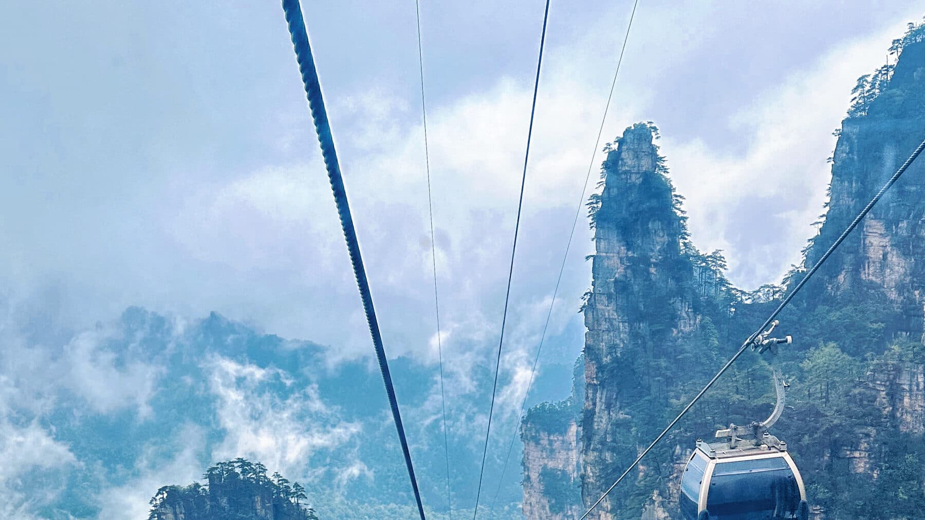 Cable car moving through misty sandstone pillars