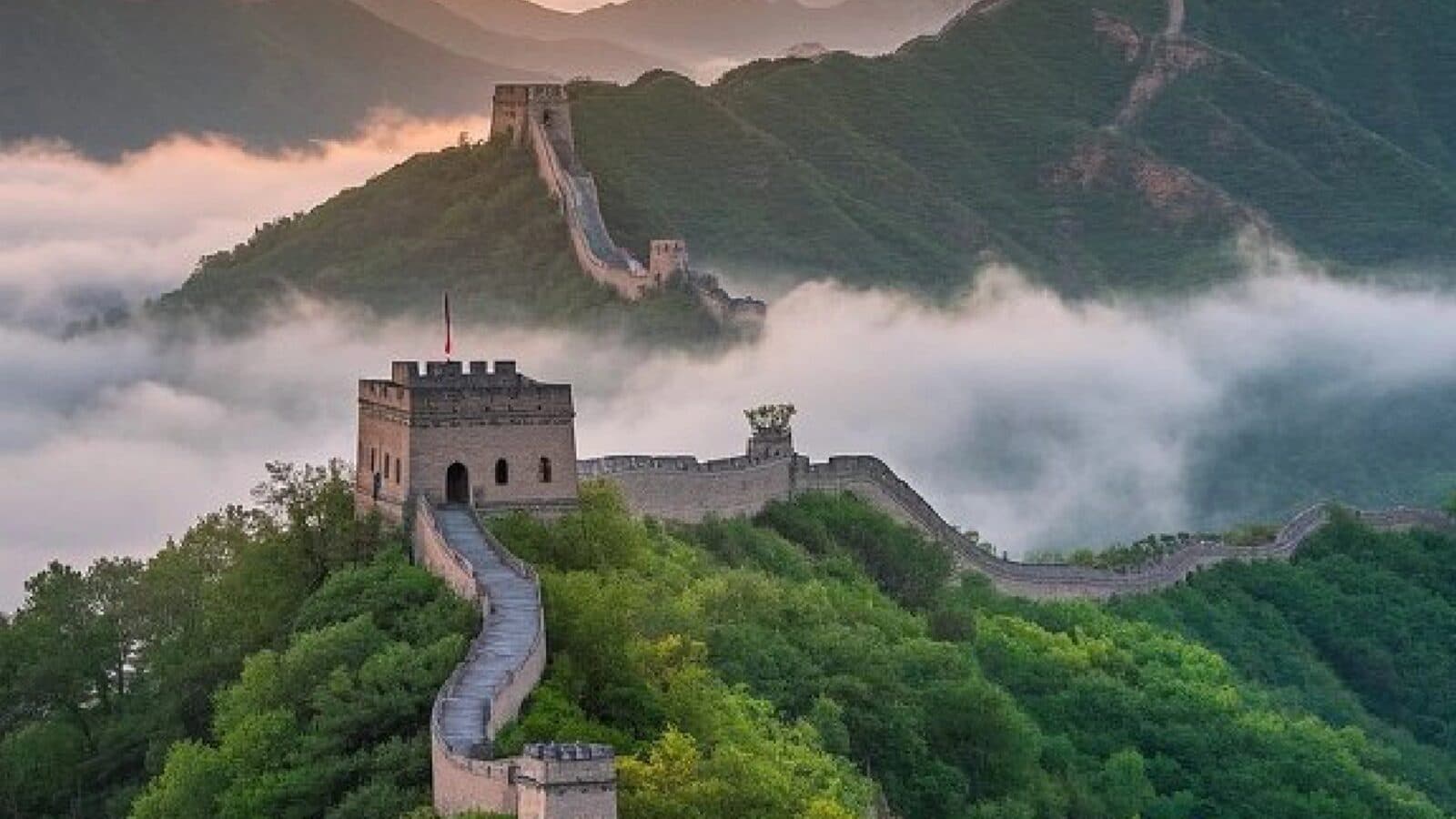 The Great Wall winding along a ridge past two watchtowers above a sea of clouds